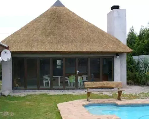 Thatched-roof house with glass doors and a swimming pool