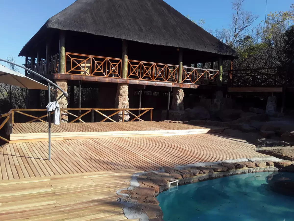 Thatched roof safari lodge with wooden deck and swimming pool