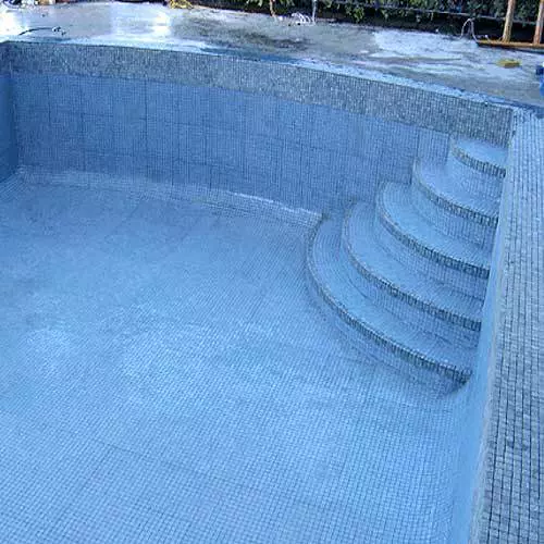 Empty swimming pool with blue mosaic tiles and steps