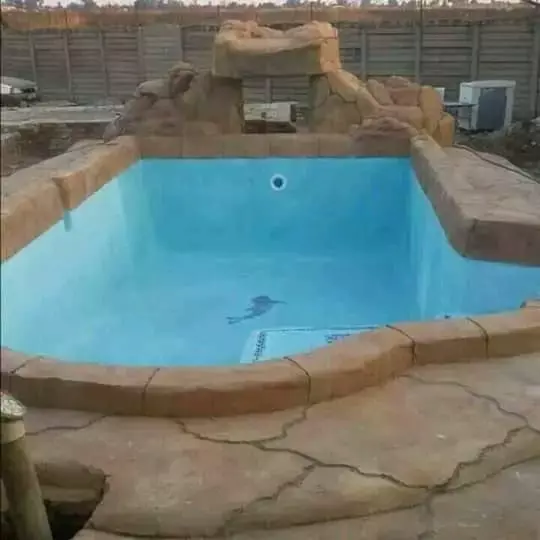 Swimming pool with artificial rock waterfall feature