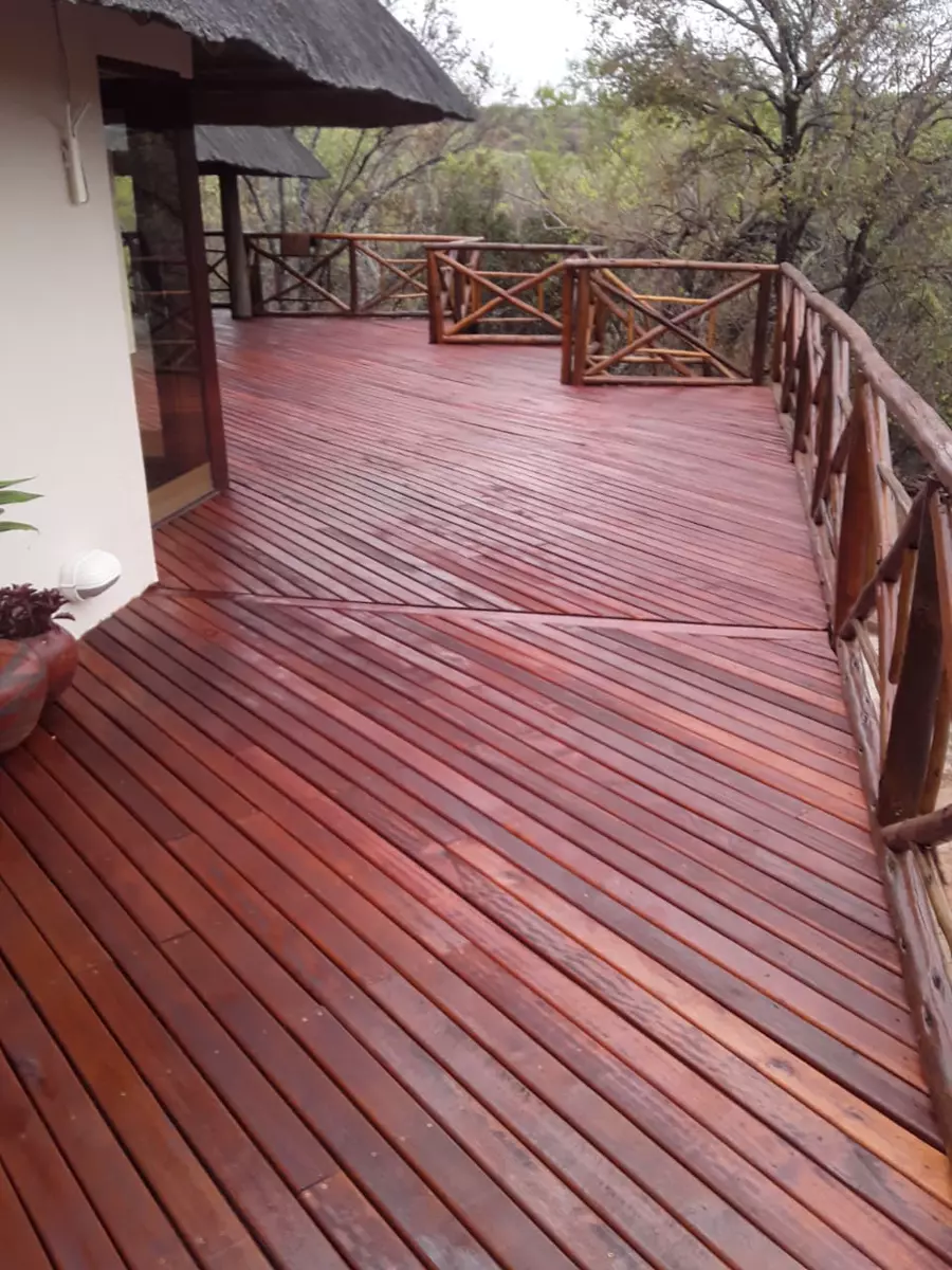 Wooden deck with railings and thatched roof overlooking a forest